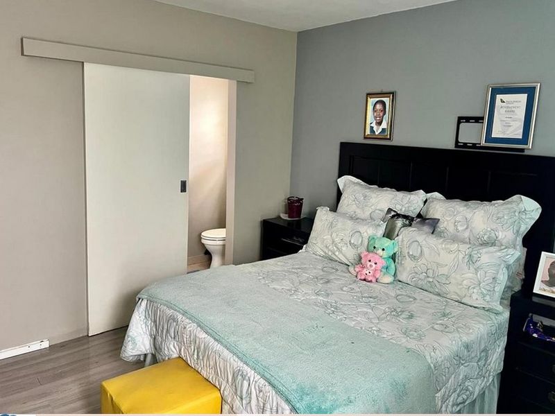 A well-maintained bedroom featuring modern laminate flooring and a convenient sliding door providing access to an en-suite bathroom.