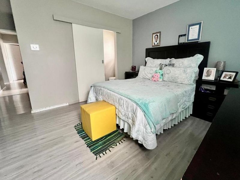 A well-maintained bedroom featuring light-toned laminate flooring and a functional sliding door leading to an adjacent space.