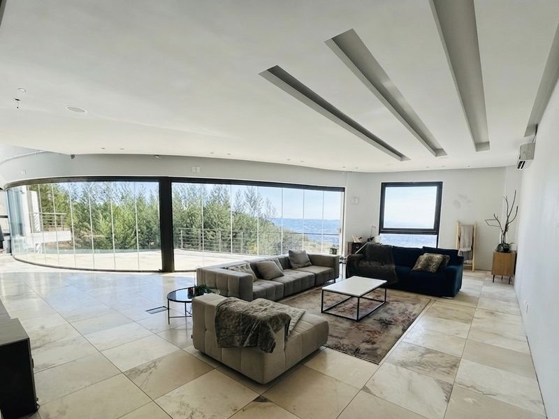 Spacious living area featuring large curved floor-to-ceiling windows with scenic views, marble flooring, and modern recessed ceiling design.