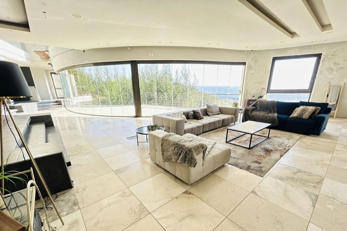 Spacious living area featuring large curved glass doors with panoramic views, stone flooring, and recessed ceiling lighting, requiring minor cosmetic wall repairs.