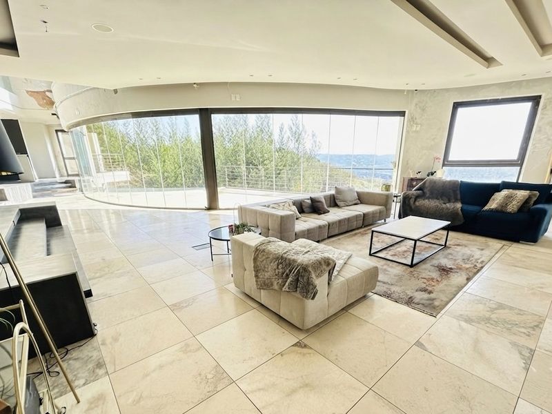 Spacious living area featuring large curved glass doors with panoramic views, stone flooring, and recessed ceiling lighting, requiring minor cosmetic wall repairs.