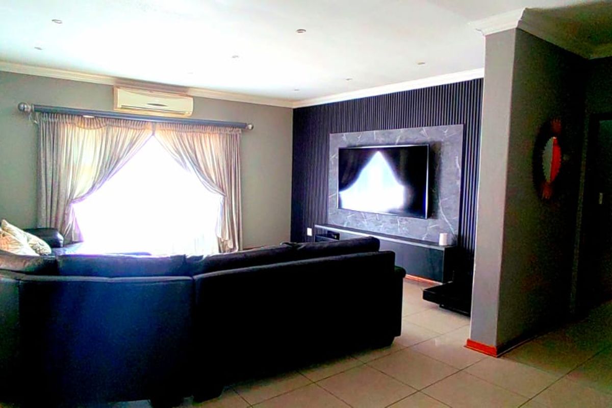 A modern living room featuring tiled flooring, recessed lighting, and a contemporary feature wall with integrated media space.