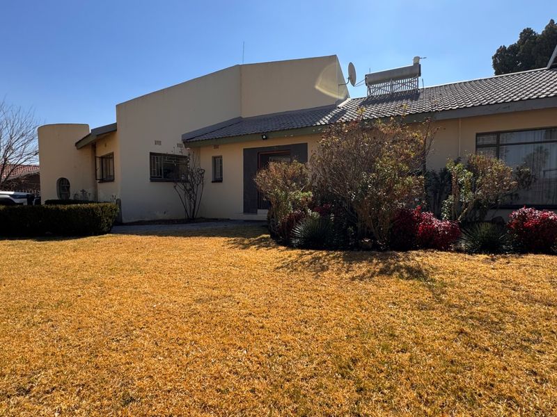 Front view of a single-story residential house featuring a tiled roof, solar water heater, and established garden area.
