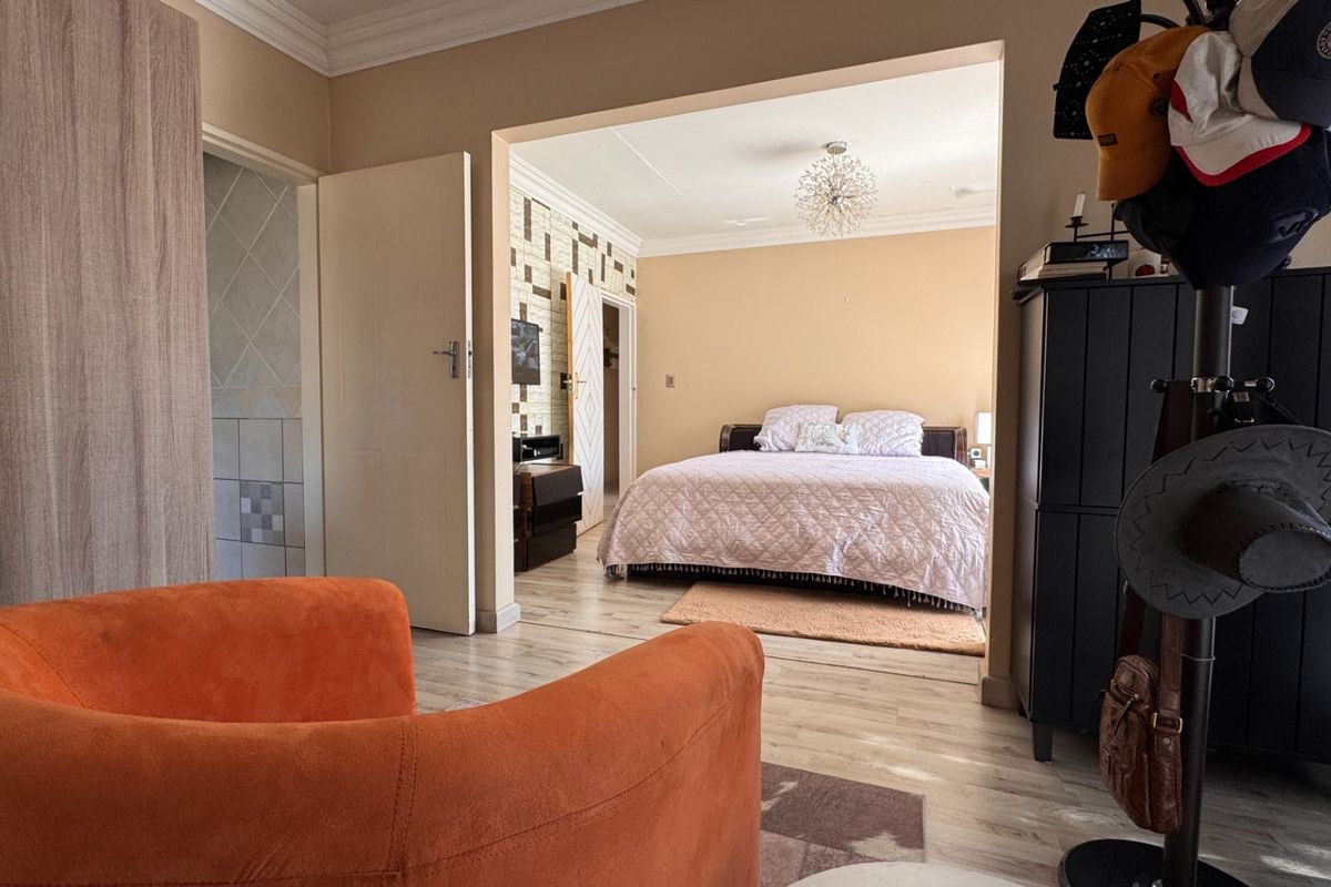 A bedroom featuring laminate flooring, built-in wardrobe storage, and decorative coving, viewed from an adjacent living space.