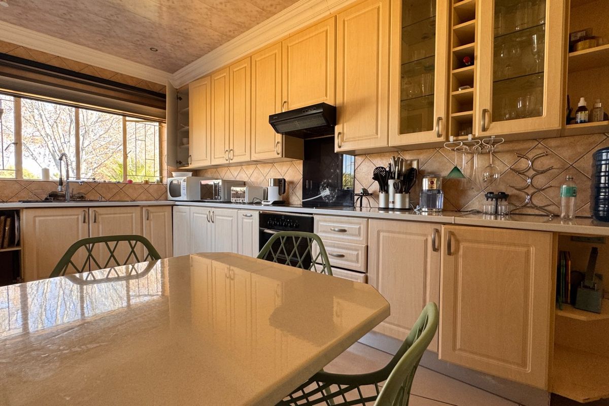 A functional kitchen featuring light wood cabinetry, stone countertops, a tiled backsplash, and integrated appliances, offering a classic and practical layout.