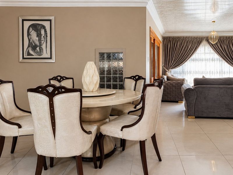 Spacious open-plan living and dining area featuring neutral wall tones, tiled flooring, and elegant cove cornicing, creating a bright and cohesive living space.