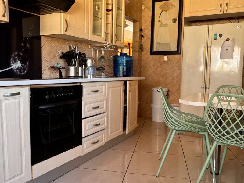 A functional kitchen featuring light-toned cabinetry, tiled backsplash, and built-in oven with extractor fan, offering a practical layout for daily meal preparation.