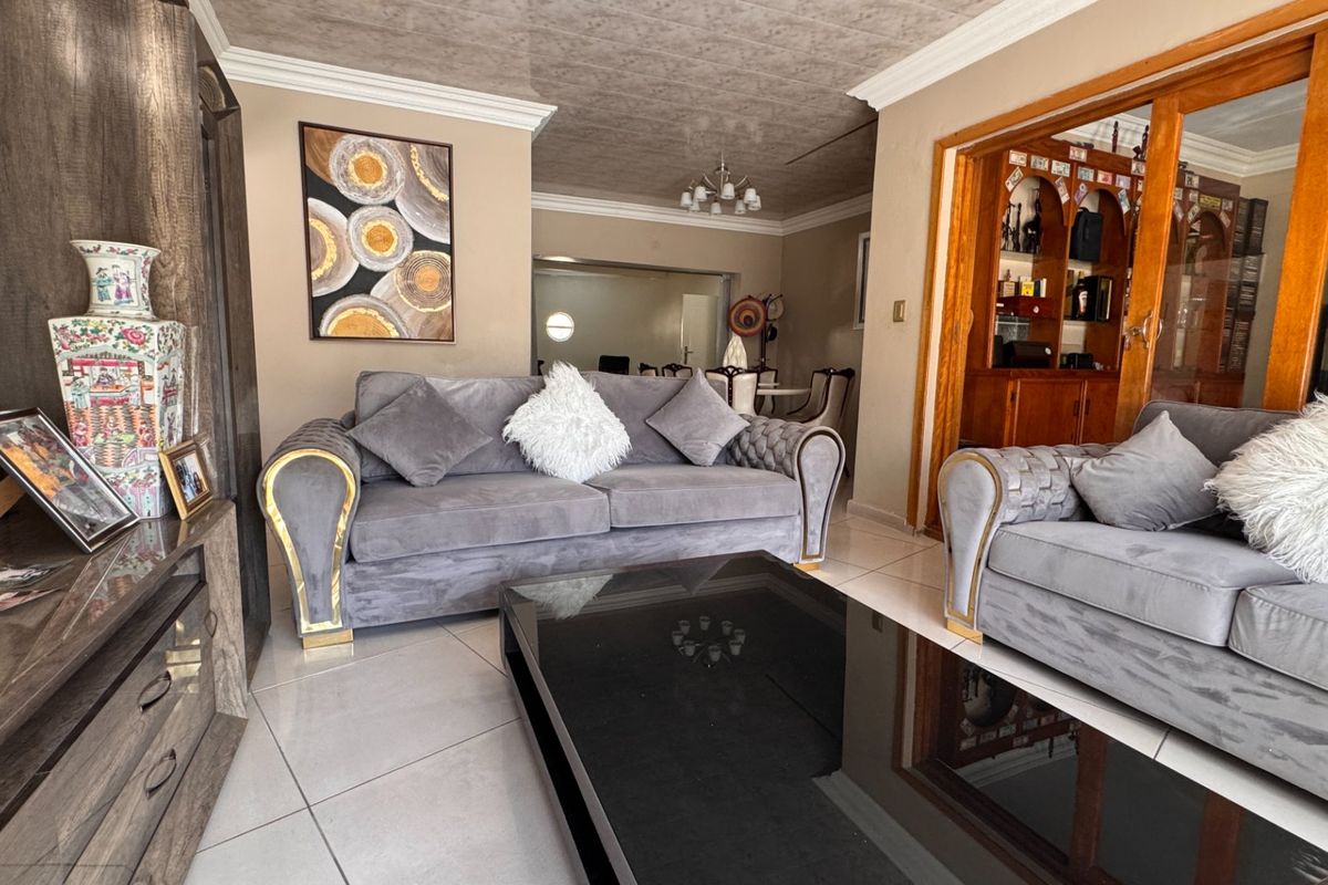 A well-maintained living room featuring tiled floors, crown molding, and integrated wooden cabinetry, providing a comfortable and functional living space.