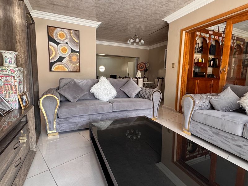 A well-maintained living room featuring tiled floors, crown molding, and integrated wooden cabinetry, providing a comfortable and functional living space.