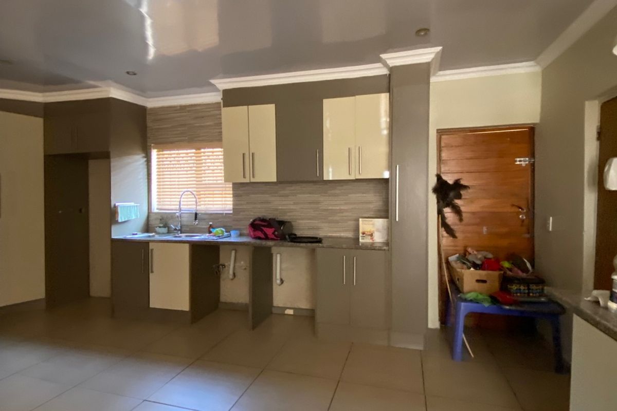 A kitchen area featuring tiled flooring, built-in cabinetry, and a tiled backsplash, currently requiring minor repairs to cabinetry and plumbing fixtures.
