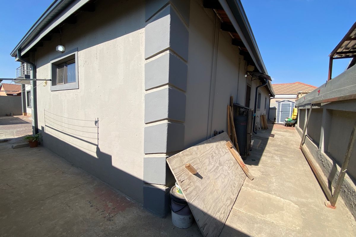 A view of the rear exterior area featuring concrete paving, perimeter walling, and exterior building finishes.