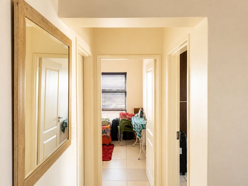 A bright hallway featuring tiled flooring and neutral walls, providing access to adjacent rooms within the apartment.
