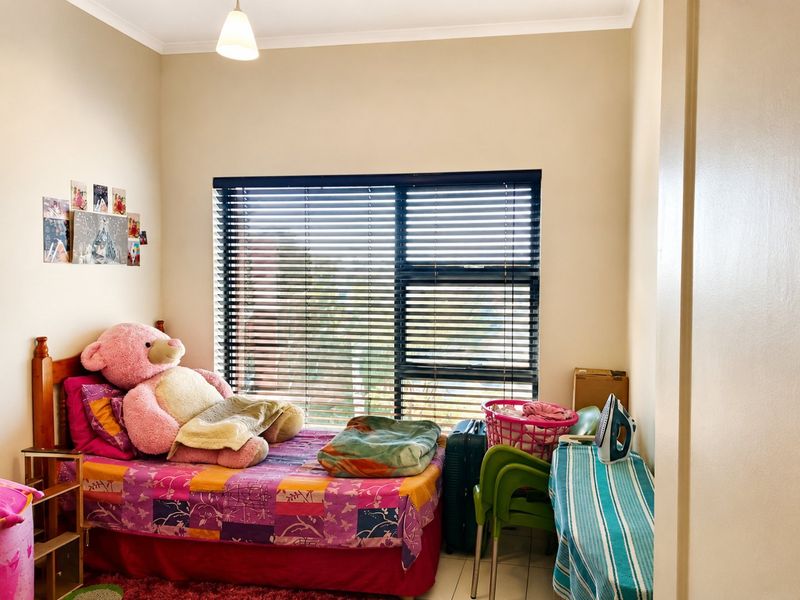 A bedroom featuring tiled flooring and venetian blinds, providing a functional space with natural light.