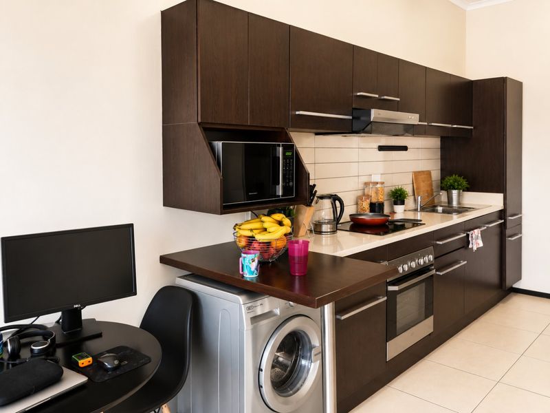 Modern kitchen featuring dark wood cabinetry, integrated appliances, subway tile backsplash, and tiled flooring, providing a functional and compact cooking space.