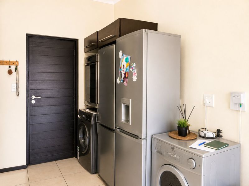 A functional laundry area featuring tiled flooring, built-in cabinetry, and space for multiple appliances.