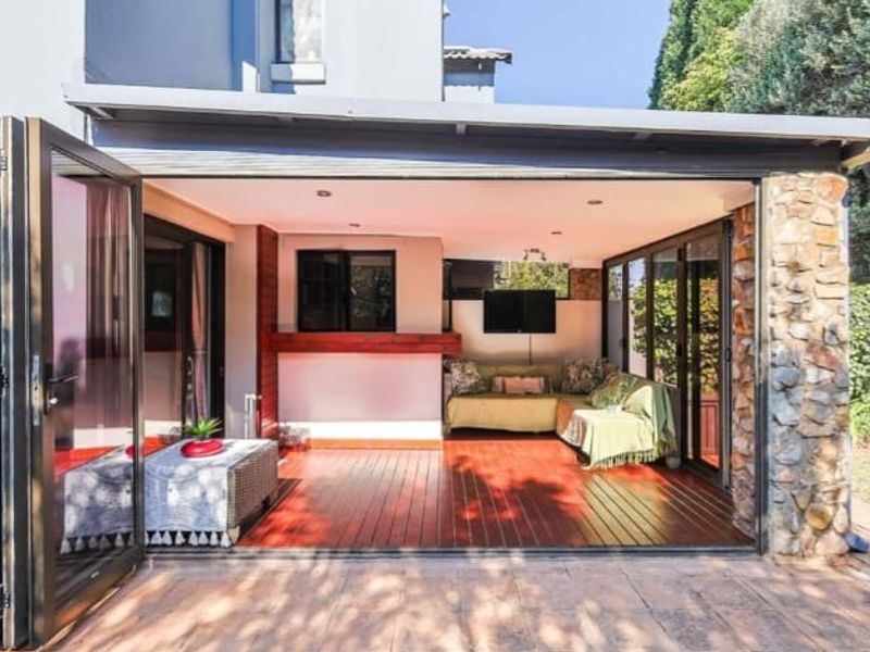 A spacious covered patio featuring timber decking, stone cladding accents, and large stacking doors that provide seamless indoor-outdoor flow.