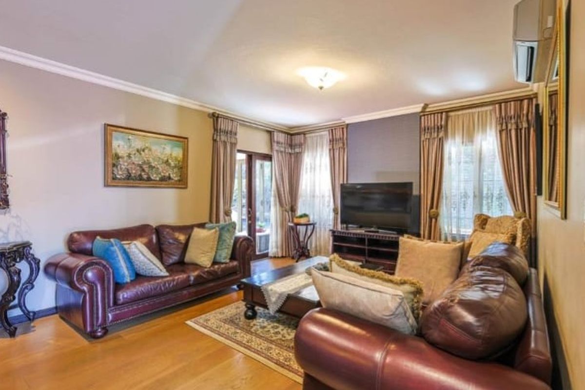 A well-maintained living room featuring hardwood flooring, crown molding, and a wall-mounted air conditioning unit, with direct access to the outdoor area.