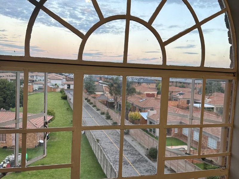An elevated view of the surrounding residential neighborhood captured through a large, arched metal-framed window.