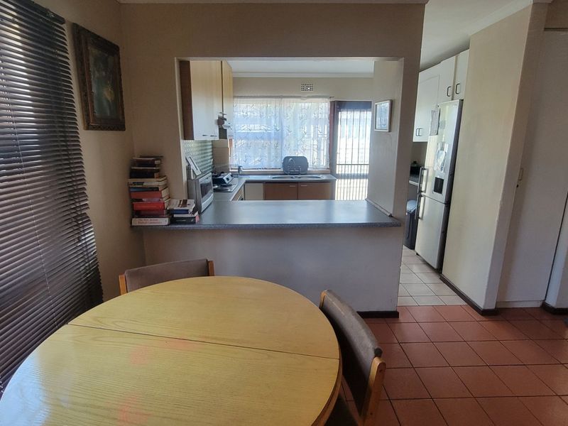 Open plan kitchen and dining area featuring tiled flooring, a breakfast bar, and functional cabinetry with direct access to the rear exterior.