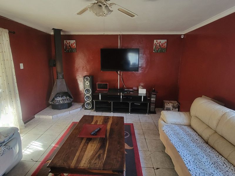A living room featuring tiled flooring, a freestanding fireplace, and a ceiling fan, providing a functional space for relaxation.