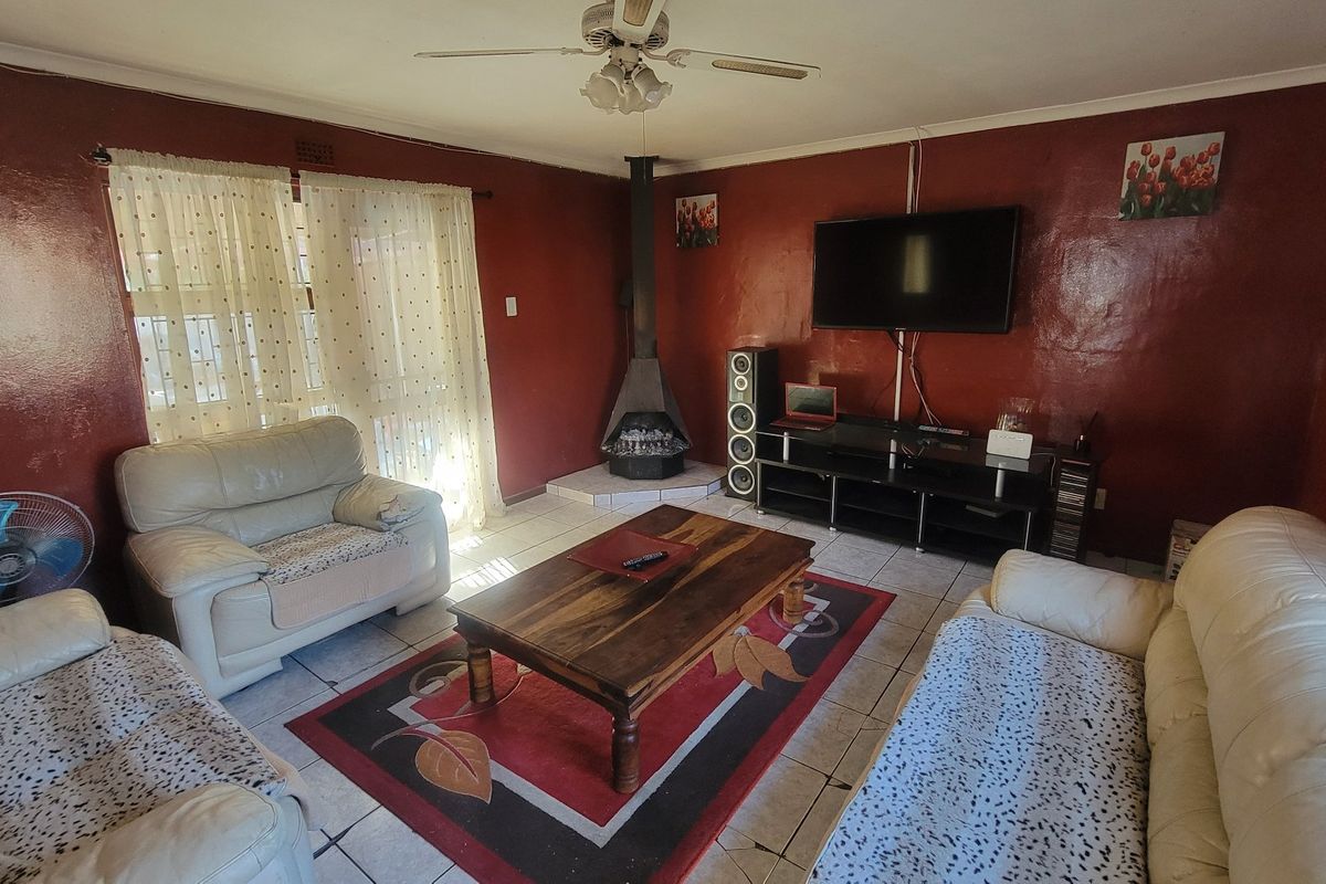 A living room featuring a freestanding fireplace, tiled flooring, and a ceiling fan, offering a functional space for relaxation.