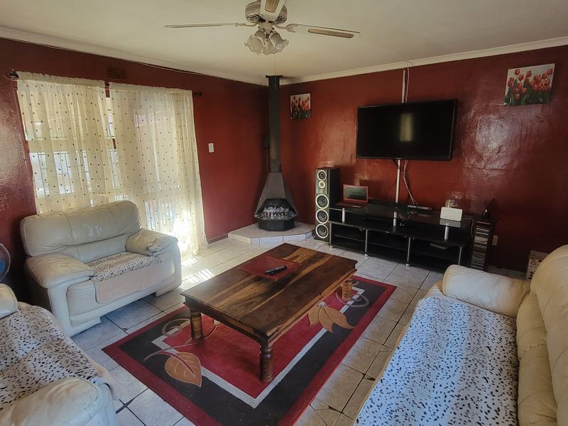 A living room featuring a freestanding fireplace, tiled flooring, and a ceiling fan, offering a functional space for relaxation.