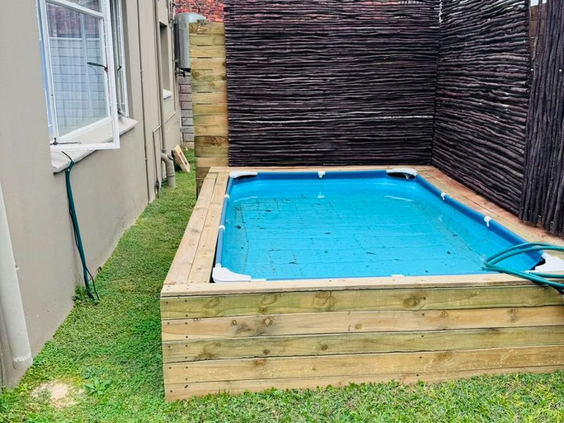 Outdoor area featuring an above-ground pool with timber decking and a privacy screen, set within a small garden space.