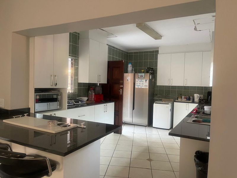 A functional kitchen featuring granite countertops, white cabinetry, and a tiled backsplash. The space requires ceiling repairs to improve its overall condition.