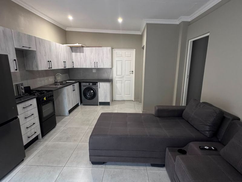 Open-plan living area featuring a modern kitchen with built-in cabinetry, gas stove, and tiled flooring throughout, creating a functional and cohesive living space.