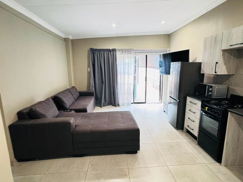 An open-plan living and kitchen area featuring tiled flooring, modern cabinetry, and a sliding door providing access to the exterior.