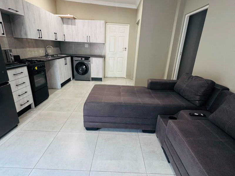 Open-plan living area featuring a modern kitchen with built-in cabinetry, tiled flooring, and recessed lighting, seamlessly integrated with the lounge space.