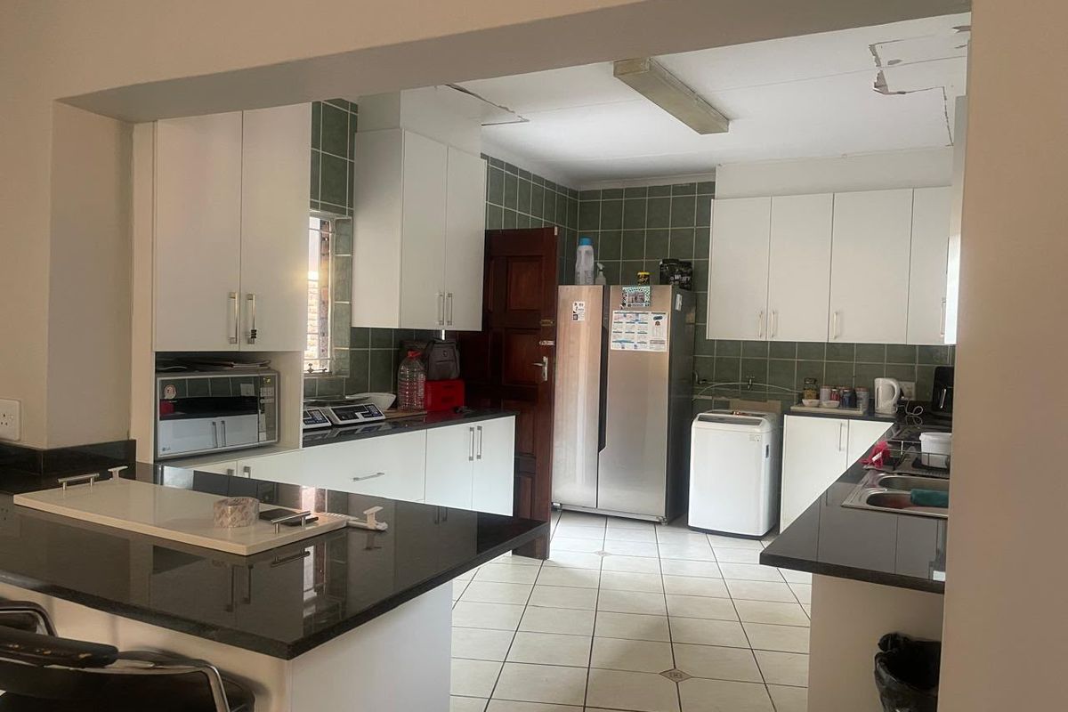 A functional kitchen featuring granite countertops, white cabinetry, and a tiled backsplash. The space requires ceiling repairs to improve its overall condition.