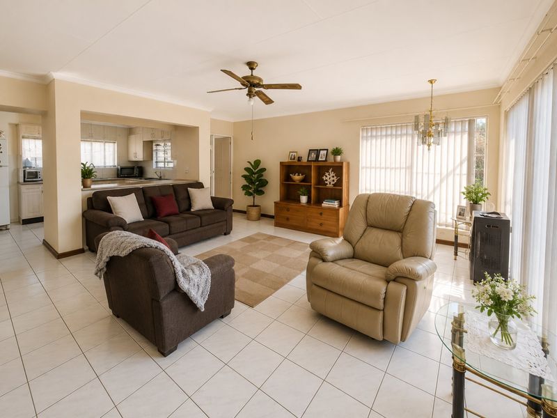 Spacious open-plan living area featuring tiled flooring, a ceiling fan, and an integrated kitchen with cabinetry, flowing into a bright lounge space.