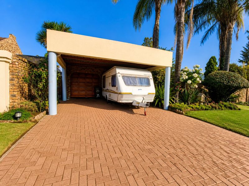 A covered carport area with a paved driveway and a secure sectional garage door entrance.