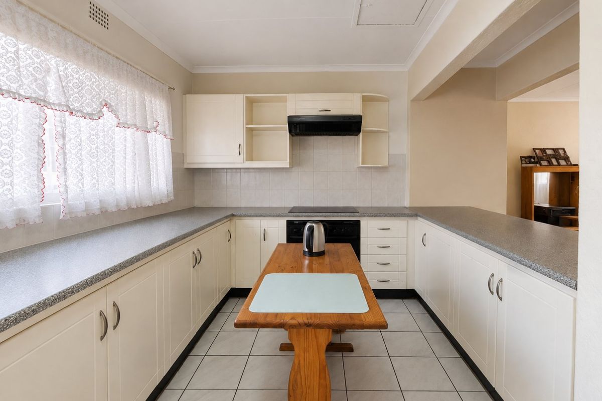 A functional kitchen featuring U-shaped cabinetry, laminate countertops, tiled backsplash, and ceramic tile flooring, offering a clean and practical layout.