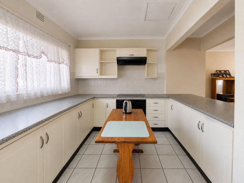A functional kitchen featuring U-shaped cabinetry, laminate countertops, tiled backsplash, and ceramic tile flooring, offering a clean and practical layout.