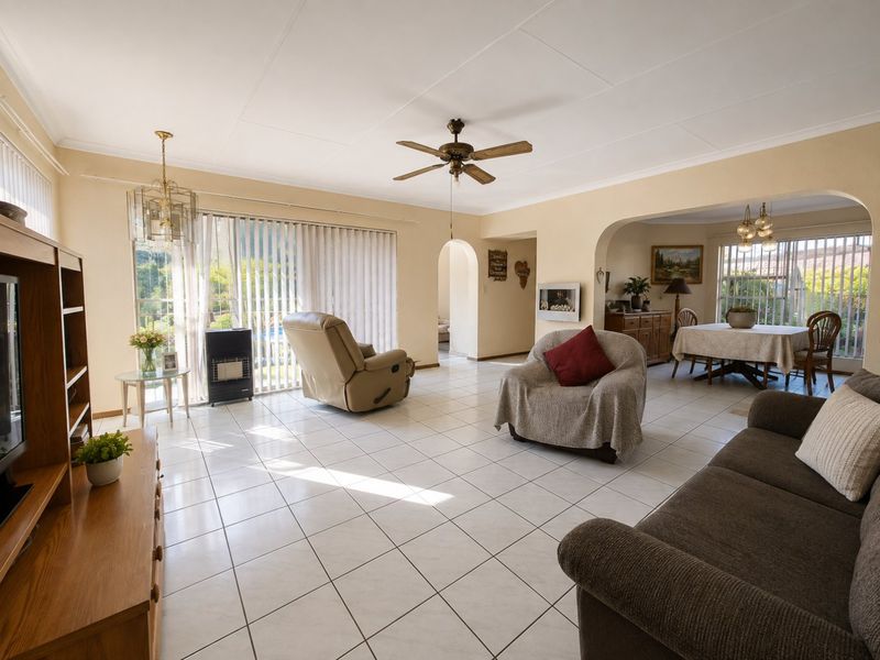 Spacious open-plan living and dining area featuring tiled flooring, a ceiling fan, and an arched transition between the two living spaces.