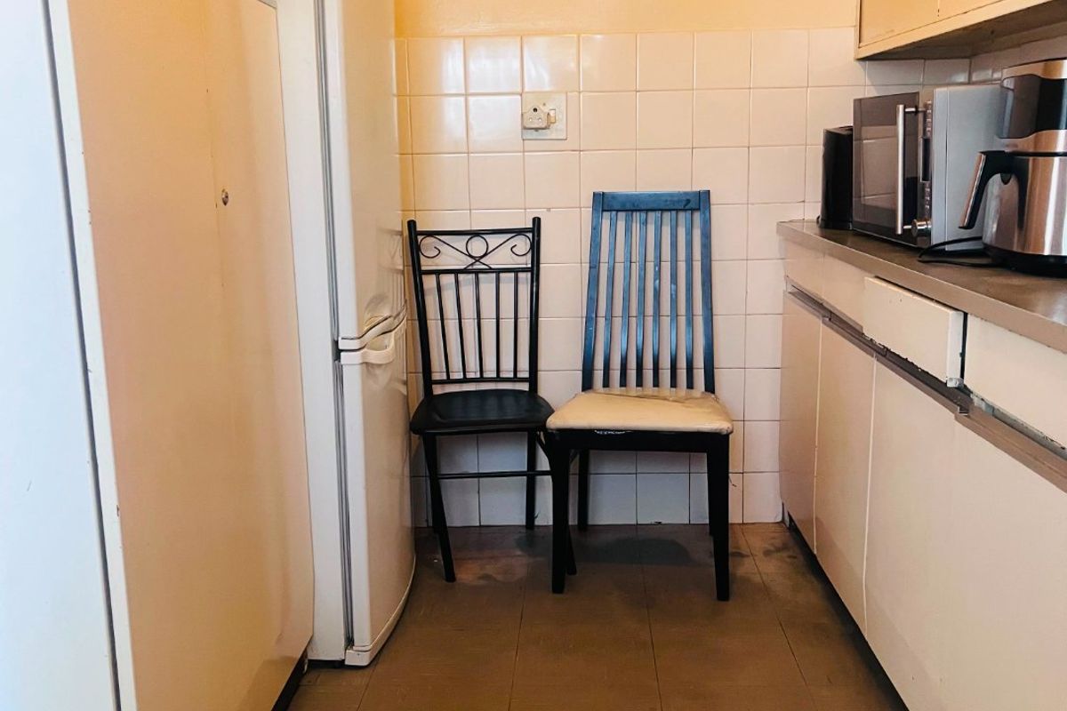 A compact kitchen featuring dated cabinetry, tiled splashbacks, and functional counter space, offering potential for a modern renovation.