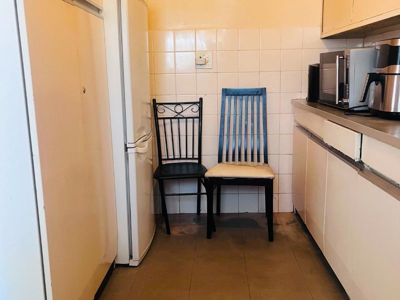 A compact kitchen featuring dated cabinetry, tiled splashbacks, and functional counter space, offering potential for a modern renovation.