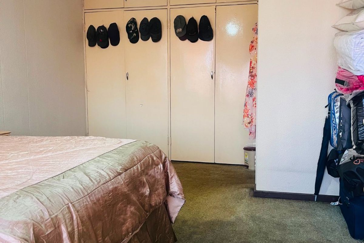 A bedroom featuring built-in cupboards with overhead storage and carpeted flooring, requiring cosmetic updates to modernize the space.