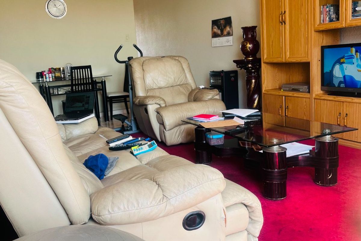 A living room featuring built-in wooden cabinetry and carpet flooring, showing visible signs of ceiling water damage and wear.