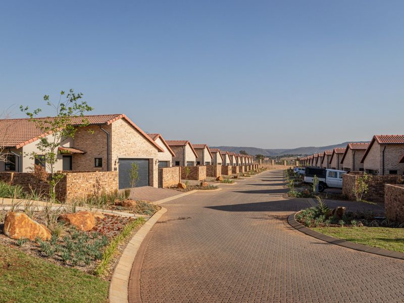 A view of a residential townhouse complex featuring uniform brick facades, tiled roofs, and paved driveways within a well-maintained estate setting.