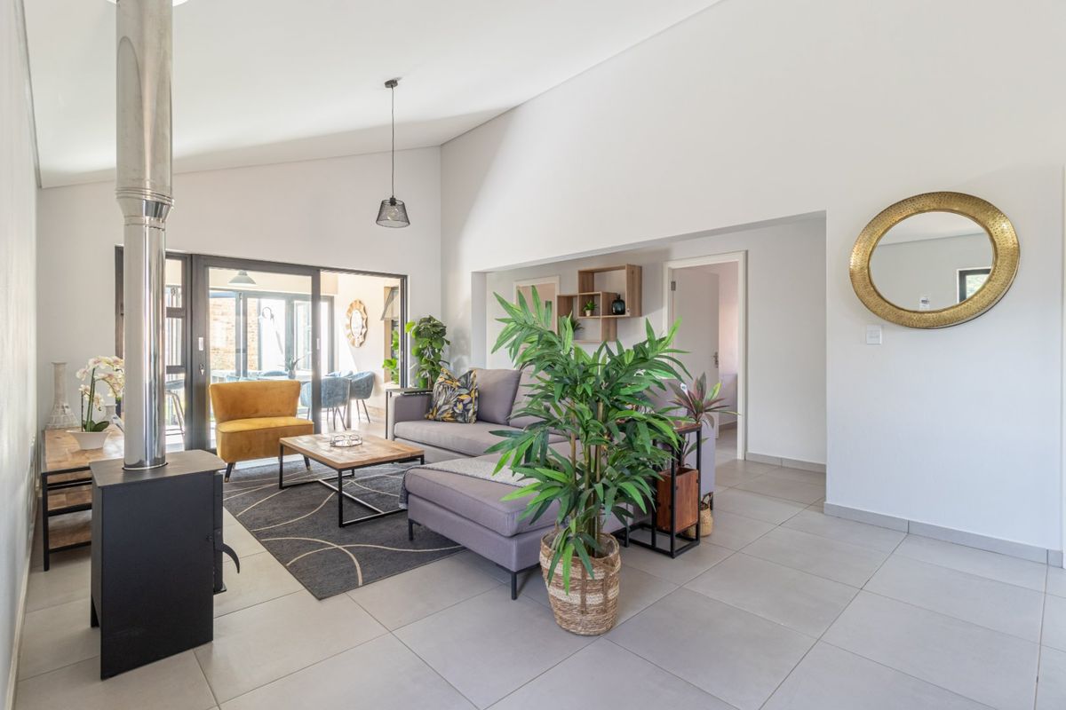 Spacious living area featuring a modern freestanding fireplace, large format floor tiles, and vaulted ceilings with seamless access to the outdoor patio.