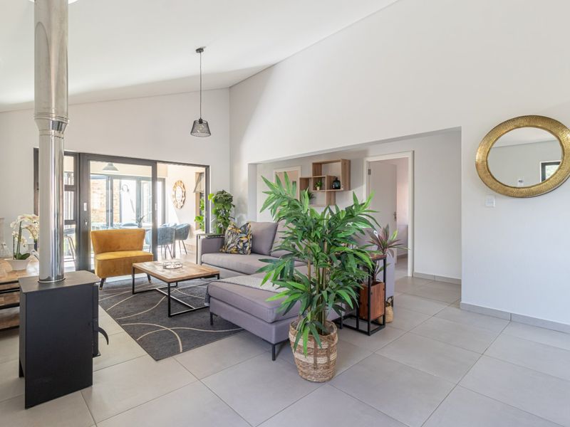Spacious living area featuring a modern freestanding fireplace, large format floor tiles, and vaulted ceilings with seamless access to the outdoor patio.