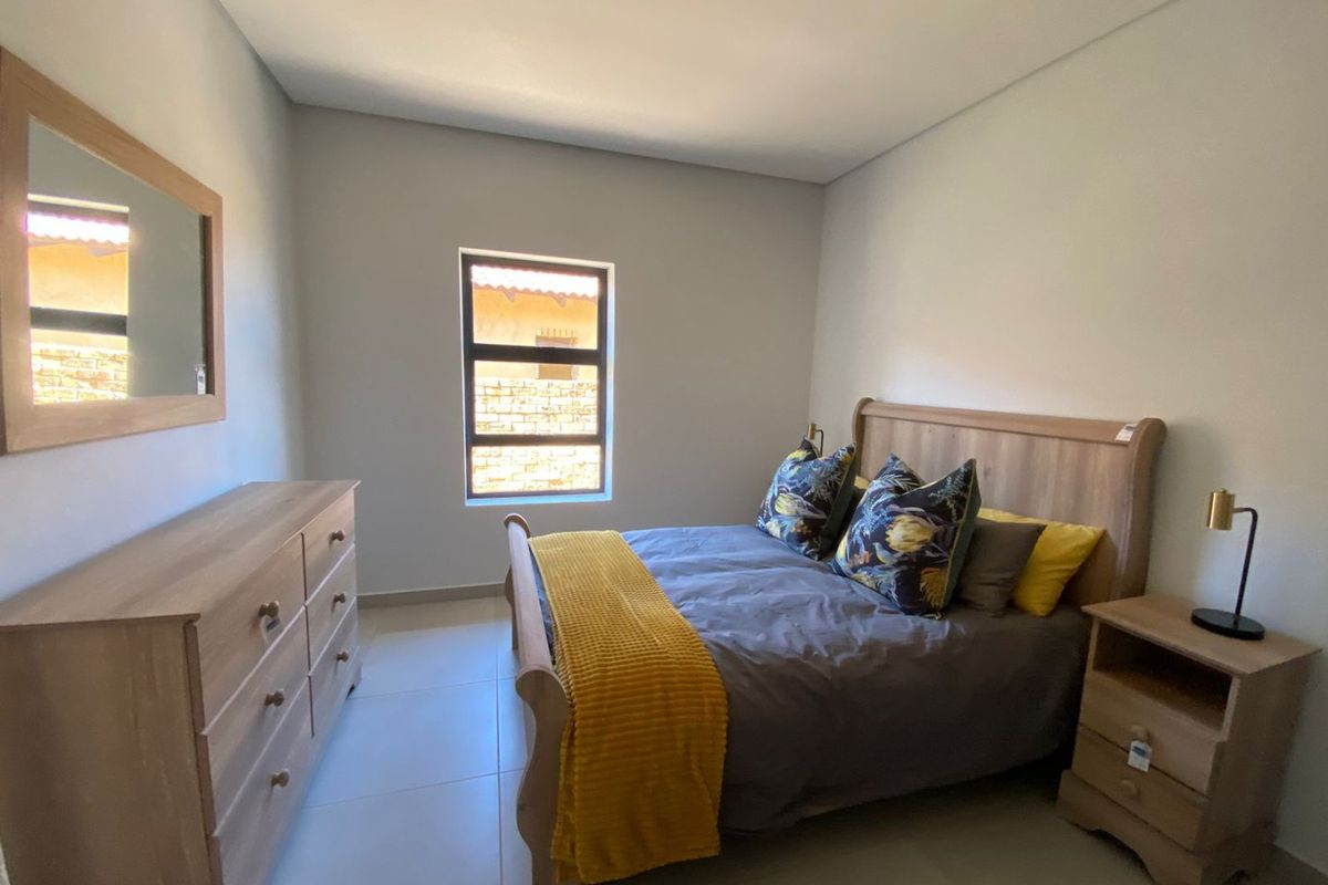A well-lit bedroom featuring neutral wall tones, tiled flooring, and a window providing natural light.