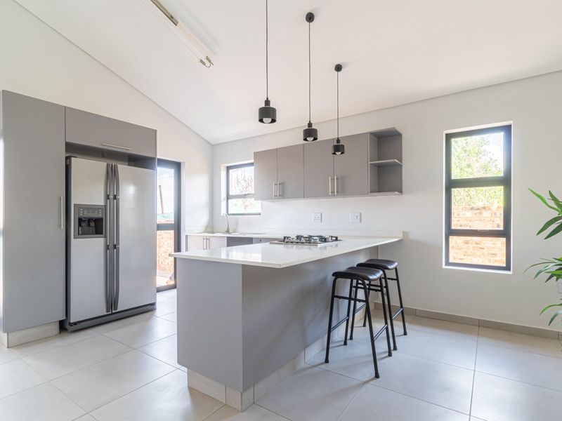 Modern kitchen featuring grey cabinetry, stone countertops, a gas hob, and tiled flooring, offering a clean and functional cooking space.