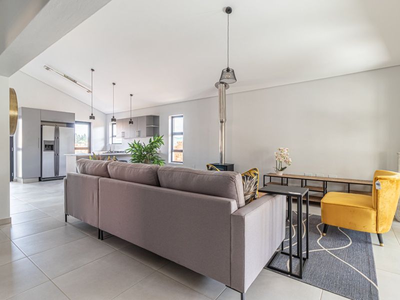 Spacious open-plan living area featuring tiled floors, a modern kitchen with built-in cabinetry, and a central fireplace, creating a bright and functional living space.