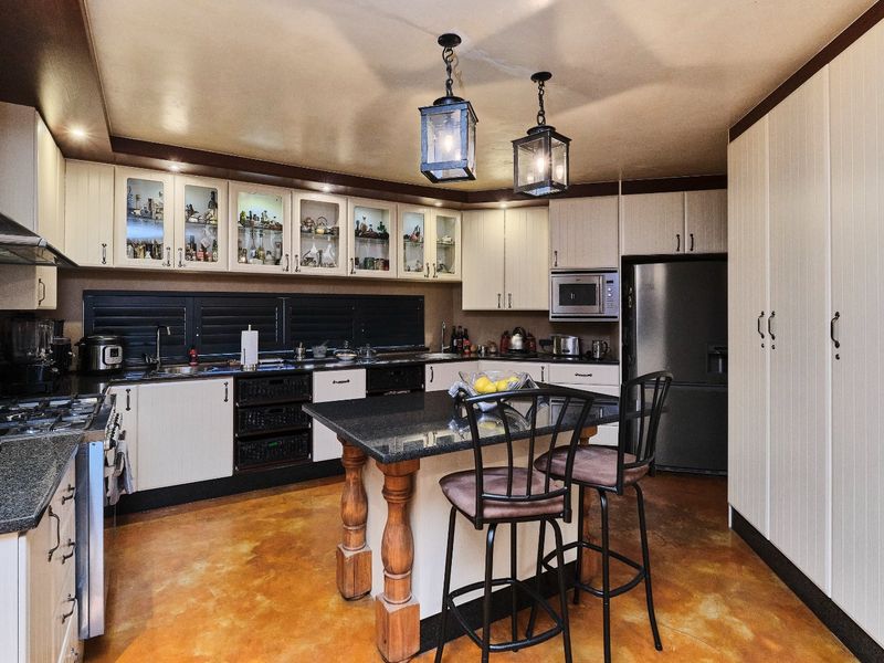 A well-appointed kitchen featuring granite countertops, a central island, built-in cabinetry, and integrated appliances, offering a functional and classic culinary space.