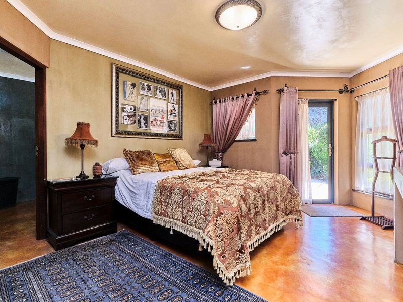 Spacious bedroom featuring polished concrete flooring, a flush mount ceiling light, and direct access to an outdoor area through a glass panel door.