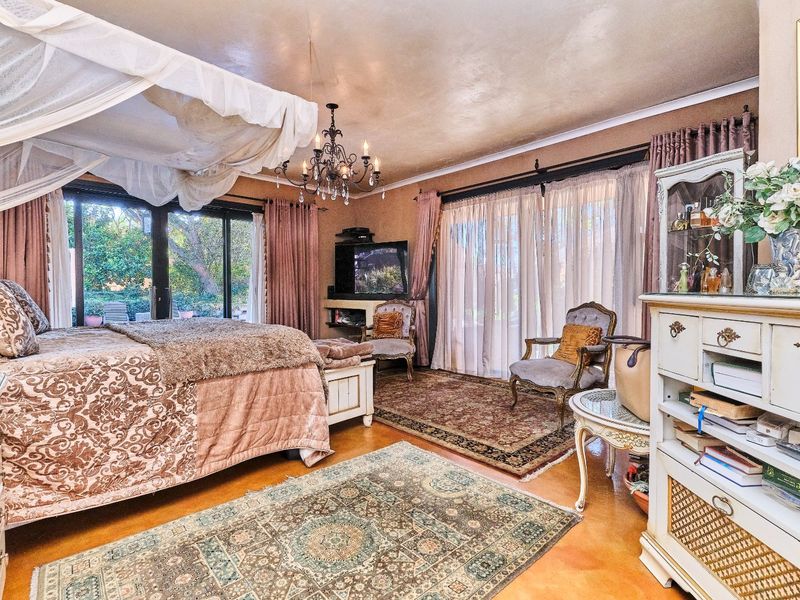 Spacious bedroom featuring polished concrete floors, a decorative chandelier, and large sliding glass doors providing direct access to the garden.